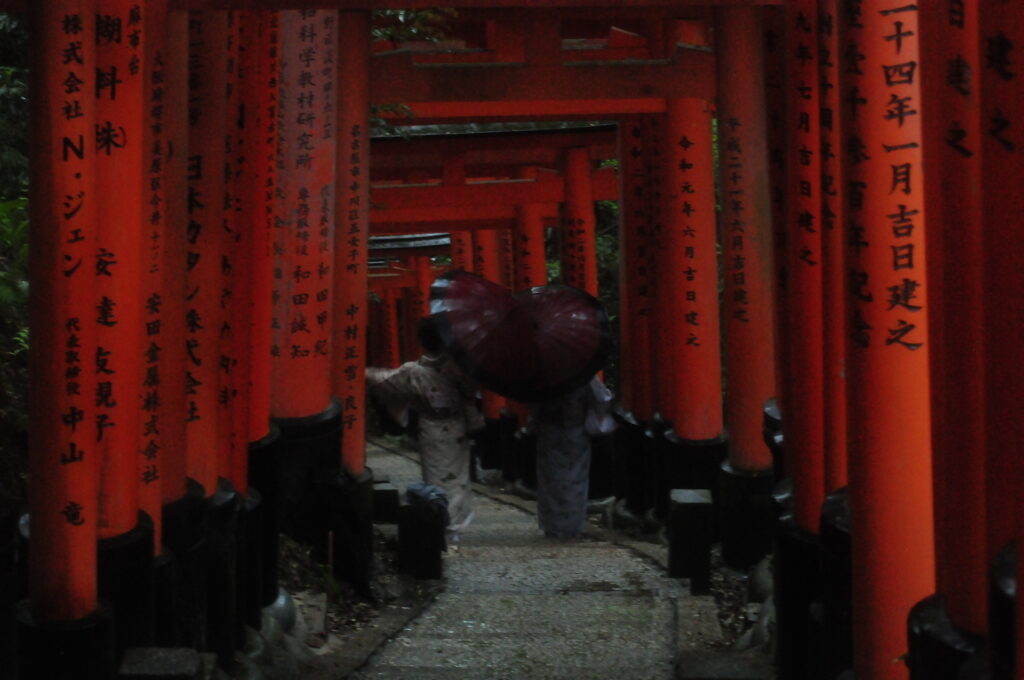 image of two people in kimonos standing between torii gates in japan