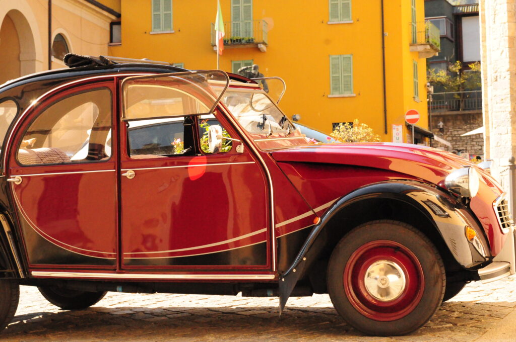 photo of old red beetle with yellow house as back round